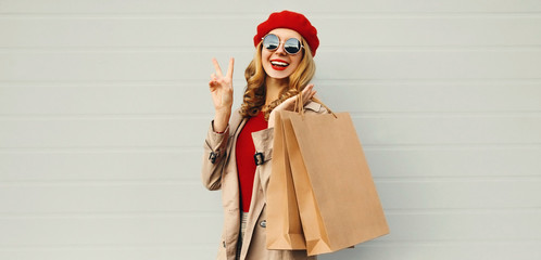 Autumn portrait of attractive smiling woman with shopping bag wearing a coat, red french beret over...