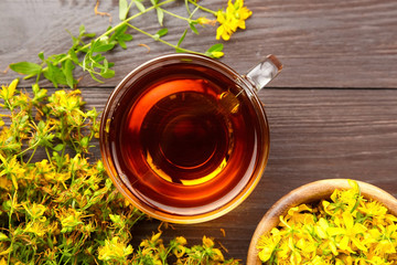 Herbal tea of Hypericum perforatum or St johns wort medicinal herb in cup with fresh flowers