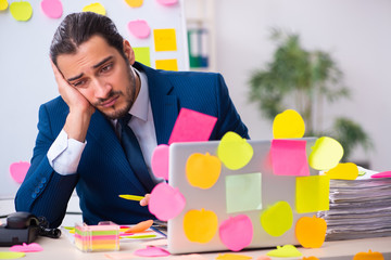 Young male employee in conflicting priorities concept
