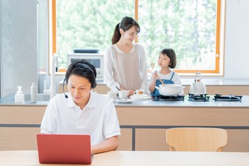 家で仕事をする父親　料理をする母子