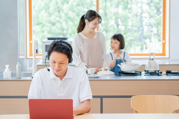 Fototapeta premium 家で仕事をする父親 料理をする母子