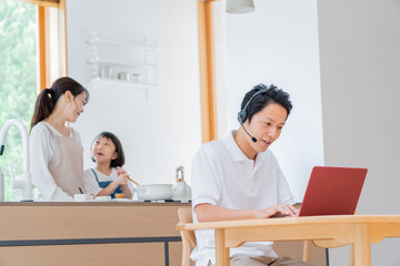 家で仕事をする父親　料理をする母子