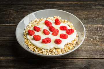 Healthy and tasty breakfast with muesli, yogurt, raspberry and honey. Selective focus.