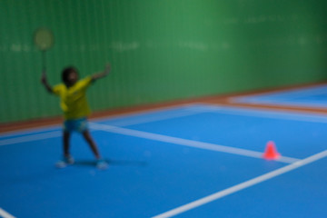 Blur background with little girl training class badminton at  gym.