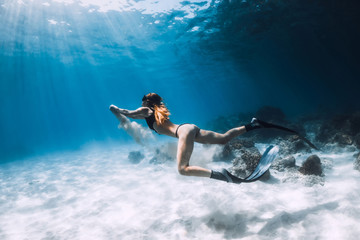 Obraz na płótnie Canvas Woman freediver posing over sandy bottom with fins. Freediving in blue ocean at Hawaii