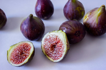 Ripe figs, purple green. Whole fruits and cut with red flesh and seeds. Grey-blue background.