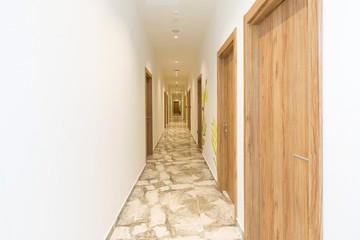 Interior of a long hotel corridor doorway with marble floor