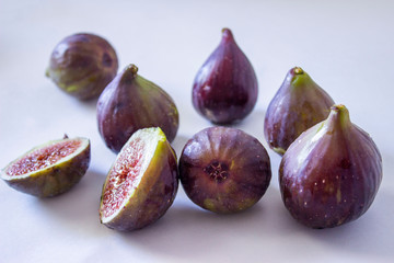 Ripe figs, purple green. Whole fruits and cut with red flesh and seeds. Grey-blue background.