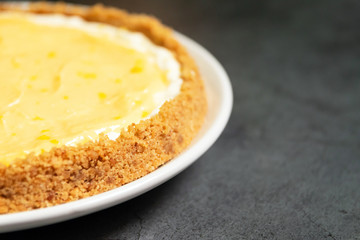 Delicious homemade honey lemon cheese pie and juicy lemoncurd on plate with copy space on black table background.