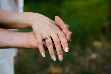 Bride and groom holding hands with wedding rings on hands.