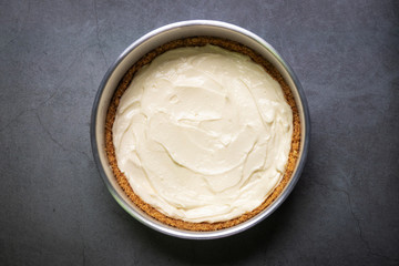 Plain cream cheese pie in a mold on black table background.