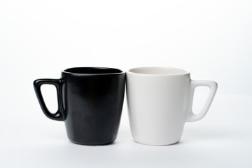 Two cups one white and one black on a white background. Each cup touches the other in various ways.