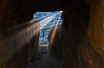 young brunette girl inside the sea waving to the sunrise sun.