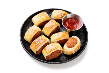 Delicious homemade sausage rolls on black plate isolated on white background
