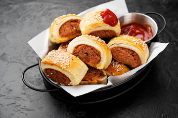 Delicious homemade sausage rolls on a black background