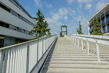 Fototapeta premium Low perspective of the stairs of the High Bridge (Hoge Brug) with its elevator. Bicycle or pedestrian bridge over Maas (Meuse) in Maastricht, sunny day in South Limburg, Netherlands