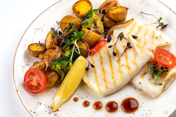 grilled squid with garnish. garnish fried potatoes with vegetables and lemon