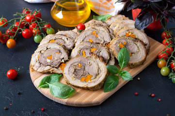 Delicious meat rolls stuffed with vegetables with cherry tomatoes and basil. Festive dish.