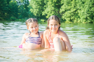 Fototapeta na wymiar In summer, girls sitting in the water are sitting on the lake on a sunny day. They are happy.