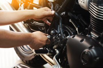 mechanic hold Hex Key Wrench working on motorcycle at motorbike garage , concept of motorcycle maintenance and repair.selective focus