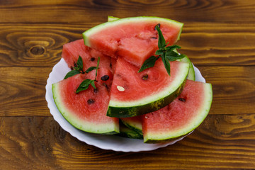 Fresh ripe sliced watermelon in white plate on a wooden table