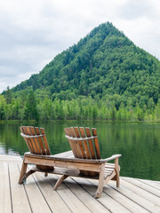 Naklejka premium Two comfortable wooden sun loungers against the backdrop of colorful mountains with emerald lake