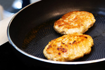 Cooking steak from fresh meat. Two meatballs fried in a metal pan. Close-up