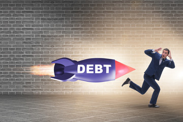 Concept of loan and debt with businessman chased by rocket