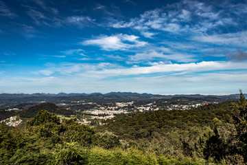 Naklejka premium city view with mountain range and bright blue sky from hill top at day
