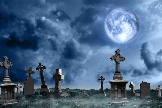 Misty graveyard with old creepy headstones under full moon on Halloween