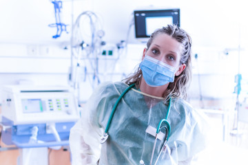 COVID19 / 2019-ncov concept: Nurse put on a protective device / equipment, to protect herself from the spread of the virus. In the background a mechanical ventilation machine