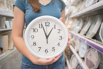 Woman is choosing a new wall clock in a store close up.