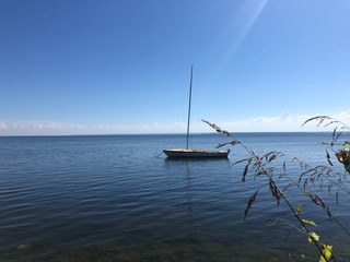 Samotna łódka na spokojnej tafli jeziora, zatoki. Łódź i piękny błękit © GregStu