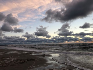 Ciemne chmury nad morską plażą po zachodzie słońca. 