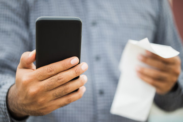 Businessman using holding smartphone and bills of payment per month. Financial buying payment income expenditure pay phone bills.