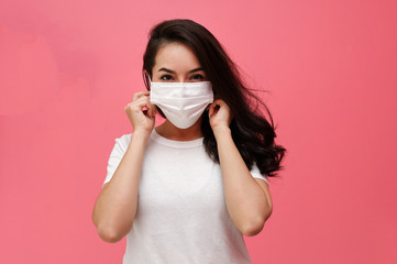 Asian woman wearing medical face mask  on pink studio background