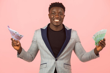 handsome young African male in a jacket, on a pink background with dollars in his hands