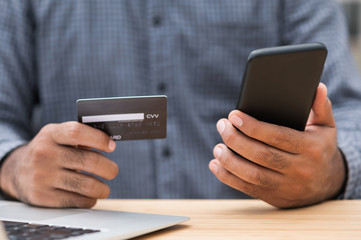 Close up businessman hand holding credit card and using smartphone and laptop computer to Financial administration. Shopping online, Internet banking concept.