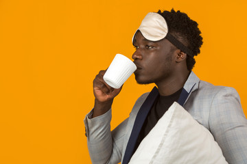 Naklejka premium handsome young african male in blazer with pillow and mug
