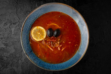 Solyanka from tomatoes, sausages, meat and olives. Balanced tasty diet food. First course