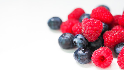 Raspberry and blueberry fruits on white background. Selected freshly picked ripe juicy berries, panoramic view