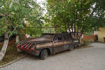 Close-up of a brutal grunge rusty car near a bar in the city of Yarovoe (Altai Territory).