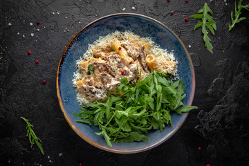Gourmet delicious penne pasta cooked with beef and cheese with arugula salad. Balanced nutritious dish. Still life for restaurant poster