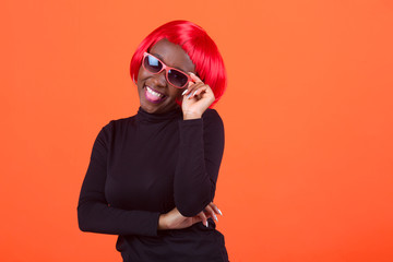 beautiful young African female, with red hair on a red background, wearing sunglasses