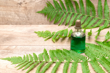 Wooden background with green fern branches and farfume in bottle, natural cosmetics concept with...