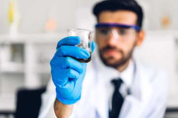Professional scientist man research and working doing a chemical experiment while making analyzing and mixing  liquid in test tube.Young science man looking sample chemical on glass at laboratory