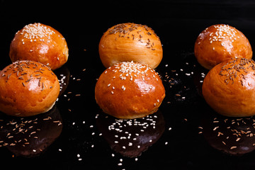 White crispy buns with sesame seeds. Photo on a black background.