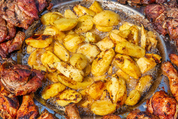 Potatoes frying in hot oil with pork and chicken
