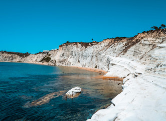 The amazing Scala dei Turchi white cliffs with beach and swimmers in Siciliy, Italy