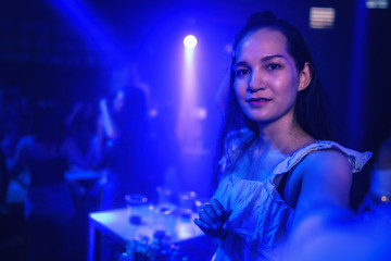young asian woman in nightclub with colorful light